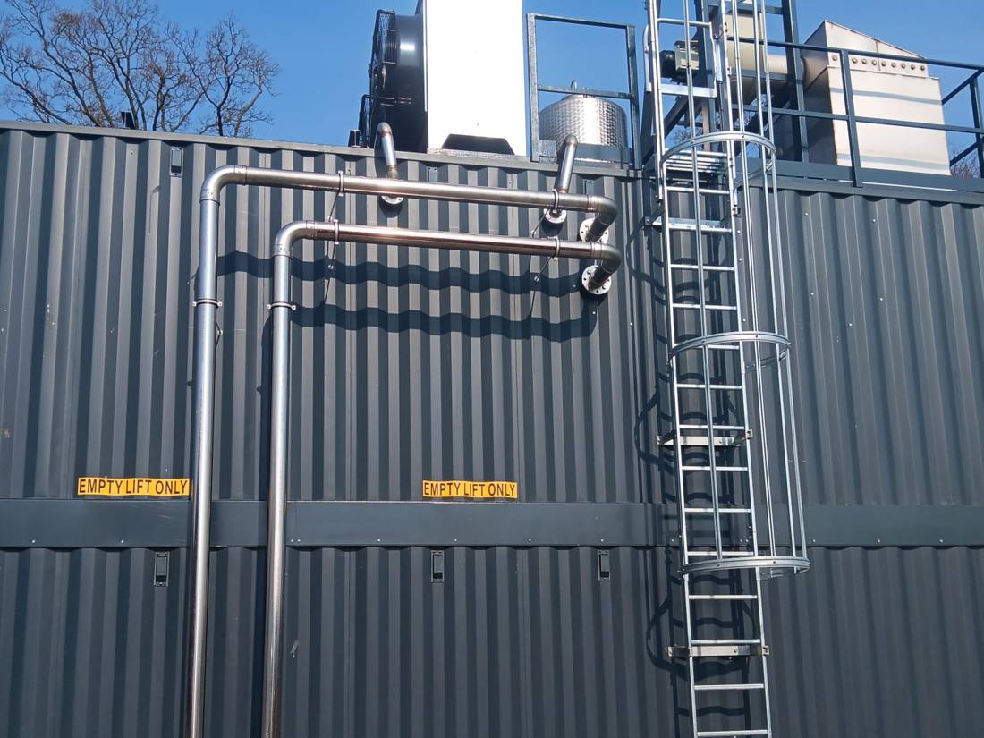 Rohrleitungen und Steigleitern an der Containerwand